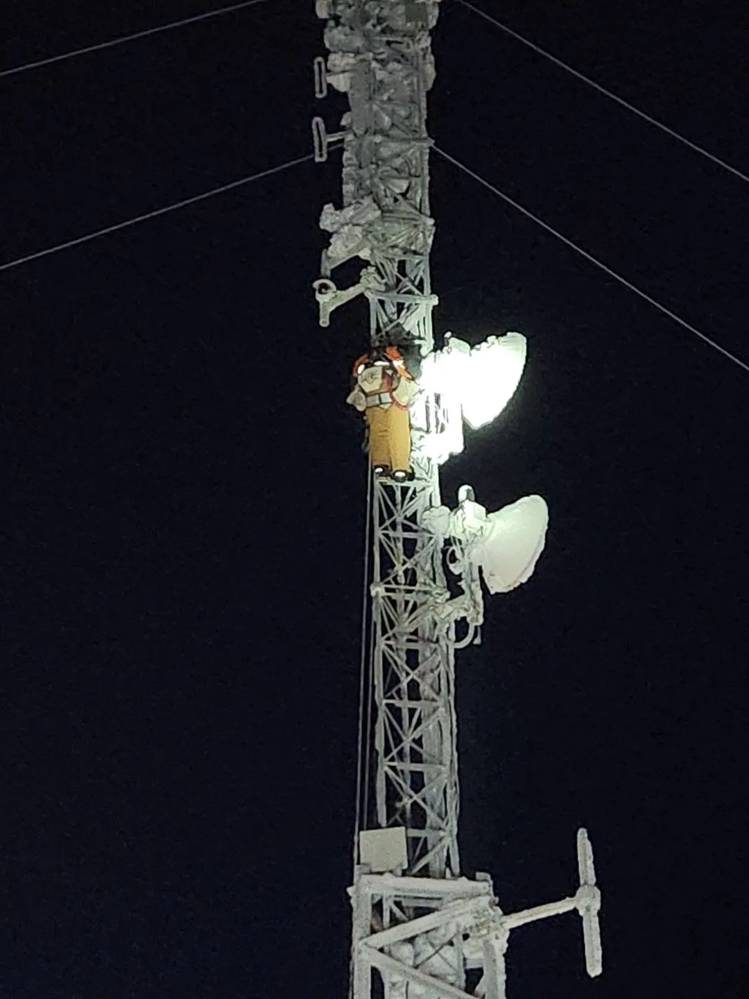 Climber working at night on iced tower with headlamp